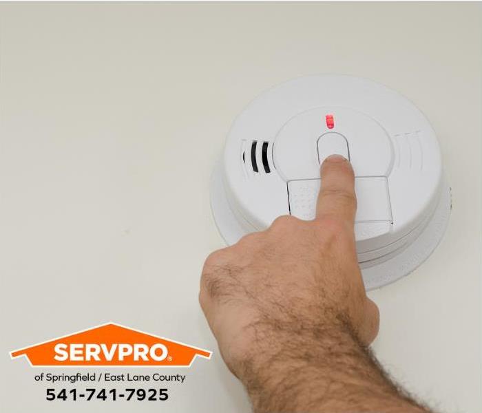 A person tests a smoke alarm during a routine home inspection.