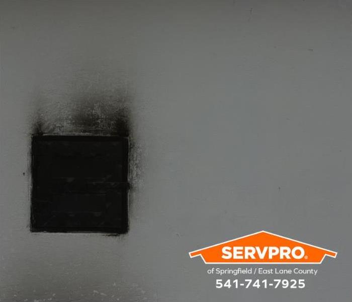 A switch plate and wall are covered in soot.